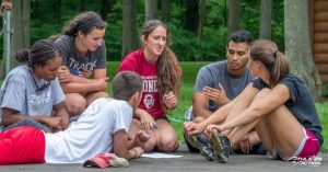 Girl talking to group sitting and laying on the ground