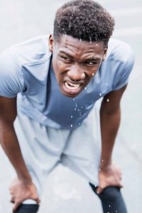 grimacing athlete with hands on knees