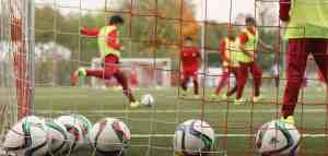 picture of young soccer players playing, taken from behind the goal net