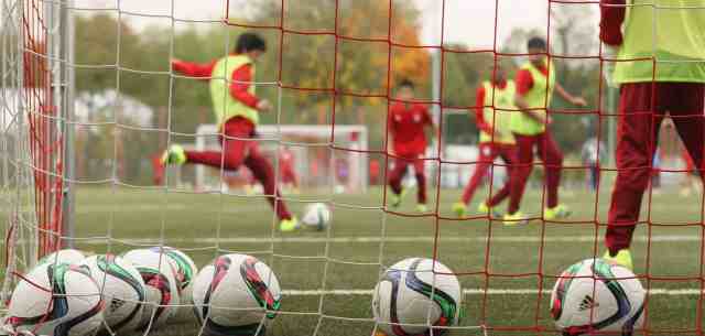 picture of young soccer players playing, taken from behind the goal net