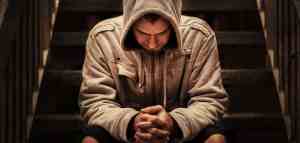 man with head bowed and hood pulled over head