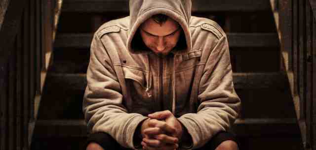 man with head bowed and hood pulled over head