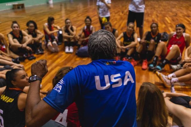 USA basketball coach talking to basketball players sitting on the court