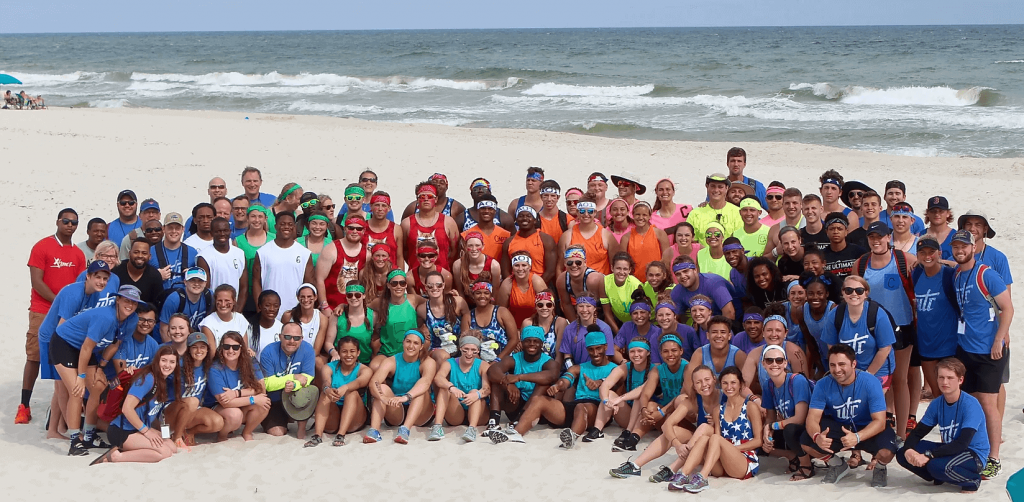 Teams of athletes posing together on a beach