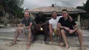 four athletes sitting on the curb alongside a road