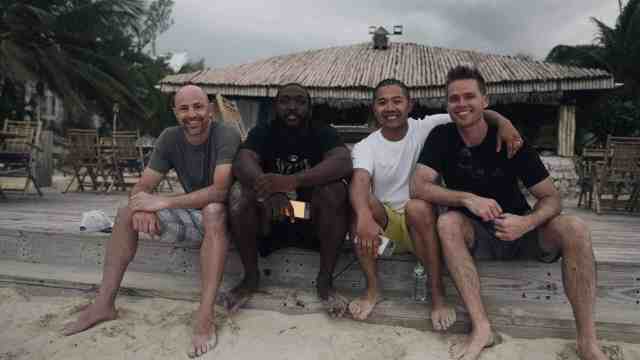 four athletes sitting on the curb alongside a road