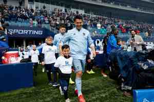 Adult soccer player walking on the field with youth soccer player
