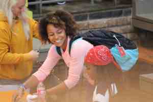 young woman wearing a backpack and smiling at a young girl