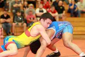 Two male athletes wrestling on the mat
