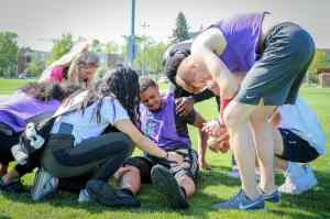 Hurt athlete surrounded by others who are praying and assisting
