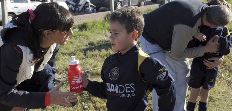 parent handing their child athlete a bottle of water
