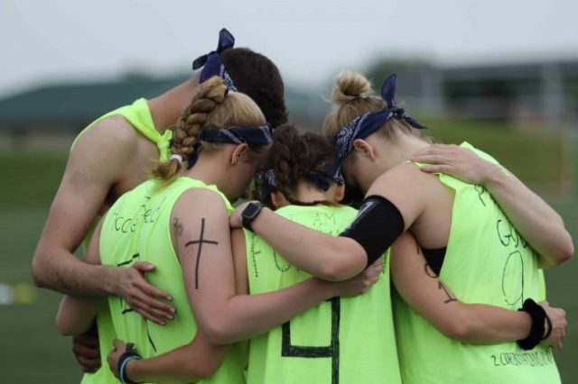 group of athletes in a prayer huddle
