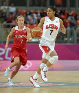 USA player Maya Moore running on the court with the basketball. A player in a red uniform is running behind her.
