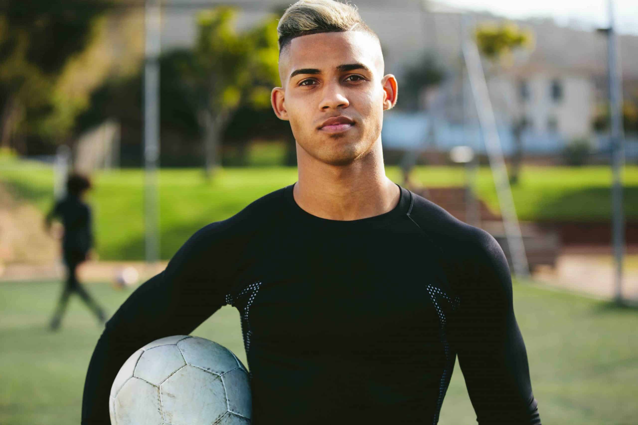 Teenage male soccer playing holding a soccer ball in hand