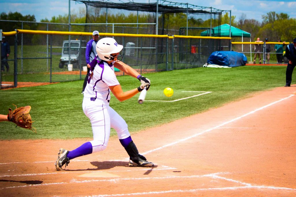 Softball player hitting the ball at the plate
