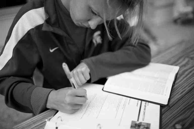 female athlete reading Bible and taking notes