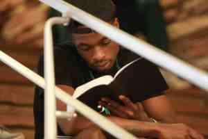man reading book on stairs