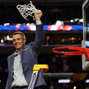 Coach Bennett on a ladder holding high the net he just cut from the basketball rim.