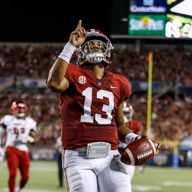 Football player on field pointing upward with one hand