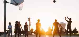 people playing basketball outside at sunset
