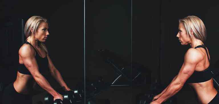 athletic woman looking at herself in the mirror