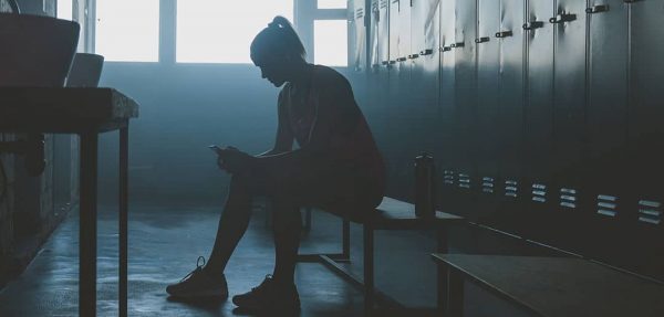 Female athlete sitting in locker room in the dark