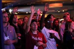 student athletes raising hands in worship at conference