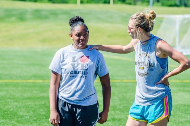 Woman athlete with hand on shoulder of another woman athlete