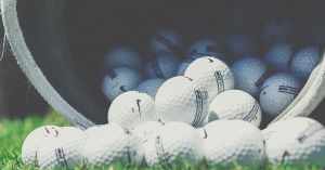 bucket of golf balls spilling onto grass