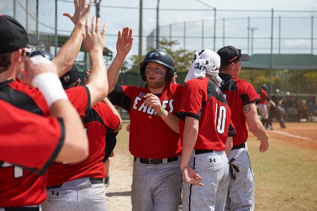 baseball players in red uniform shirts and white pants giving high 5's on the field
