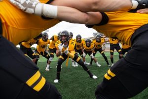 team wearing black and gold together on a field facing each other