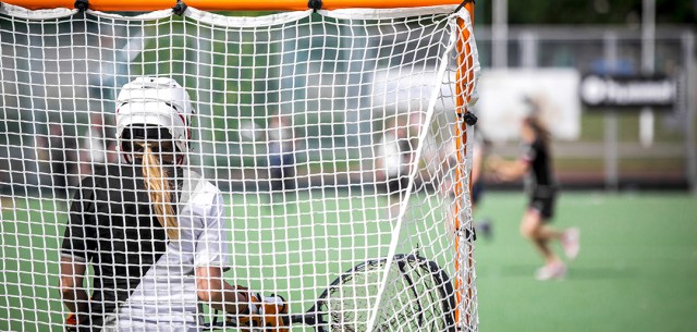 female lacrosse standing in front of net