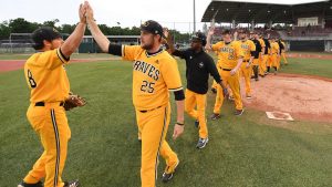 baseball team dressed in yellow uniforms crossing the field to give high fives