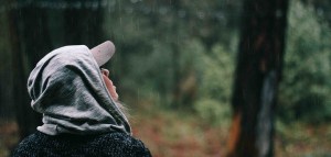 Woman standing outside in a forest watching rain