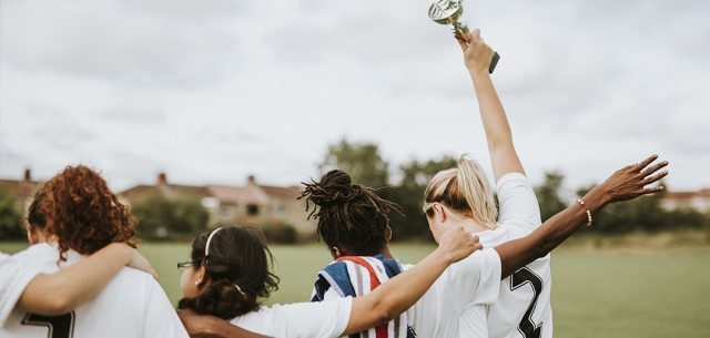female sports team. one woman holds a trophy up