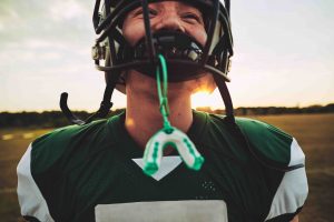 young American football player with his mouthguard hanging from his helmet