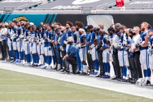 NFL Head Coach Frank Reich kneeling while team stands