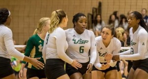 5 University of S. Florida women's team members talking to each other on a court during a game