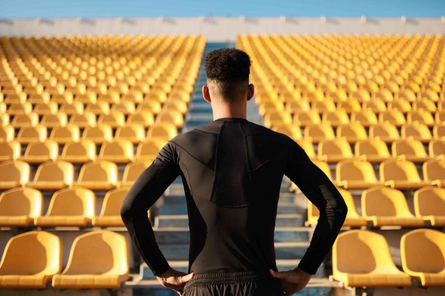 Male young adult athlete facing stadium steps