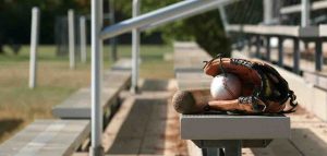 ball and baseball glove resting on outdoor bleacher