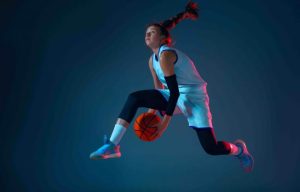 Young caucasian female basketball player on blue studio background in neon light