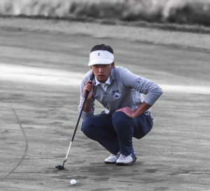 golfer is leaning down looking at the golf ball