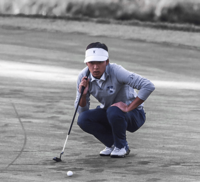 golfer is leaning down looking at the golf ball