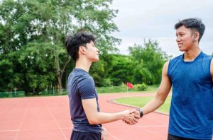 two male athletes stand and shake hands
