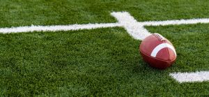 A brown leather american football on a green playing field