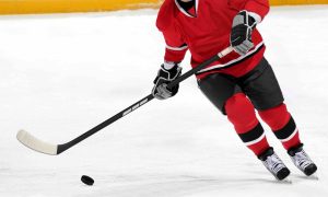 Ice hockey player dribbling puck on rink