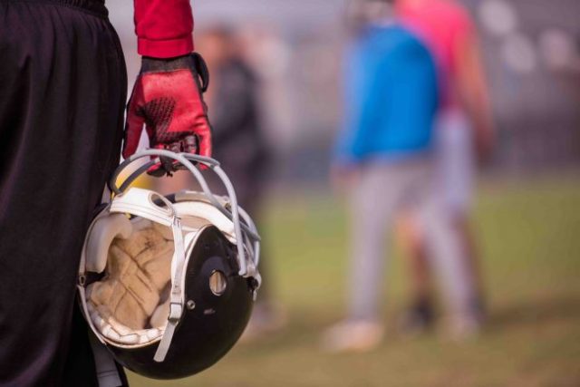 American football player holding helmet