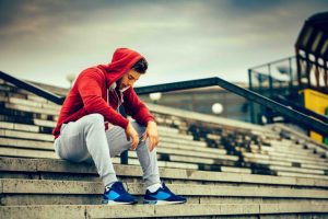 lone athlete sitting in bleachers looking down