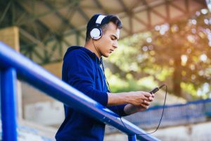 Male browsing phone while wearing headphones