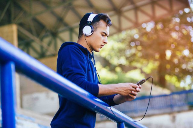 Male browsing phone while wearing headphones